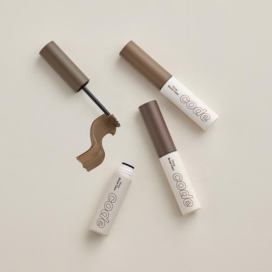 Alt Text: Natural brown brow gel from CODE GLOKOLOR, showcasing a sleek applicator and vibrant packaging.